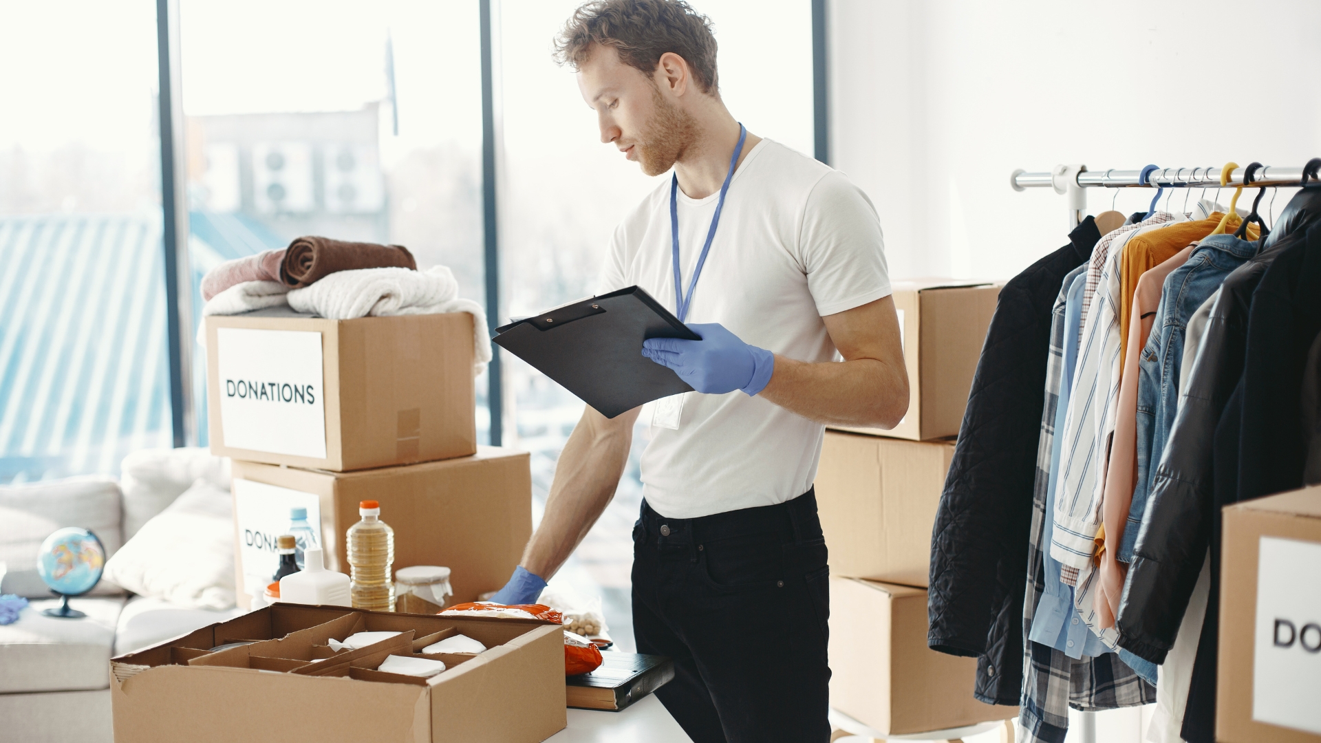 A man in white shirt and blue gloves holding a box